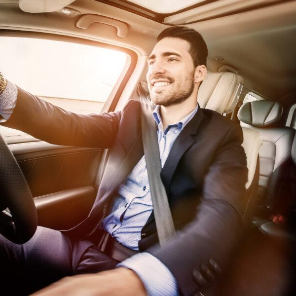 man in a suit driving a car